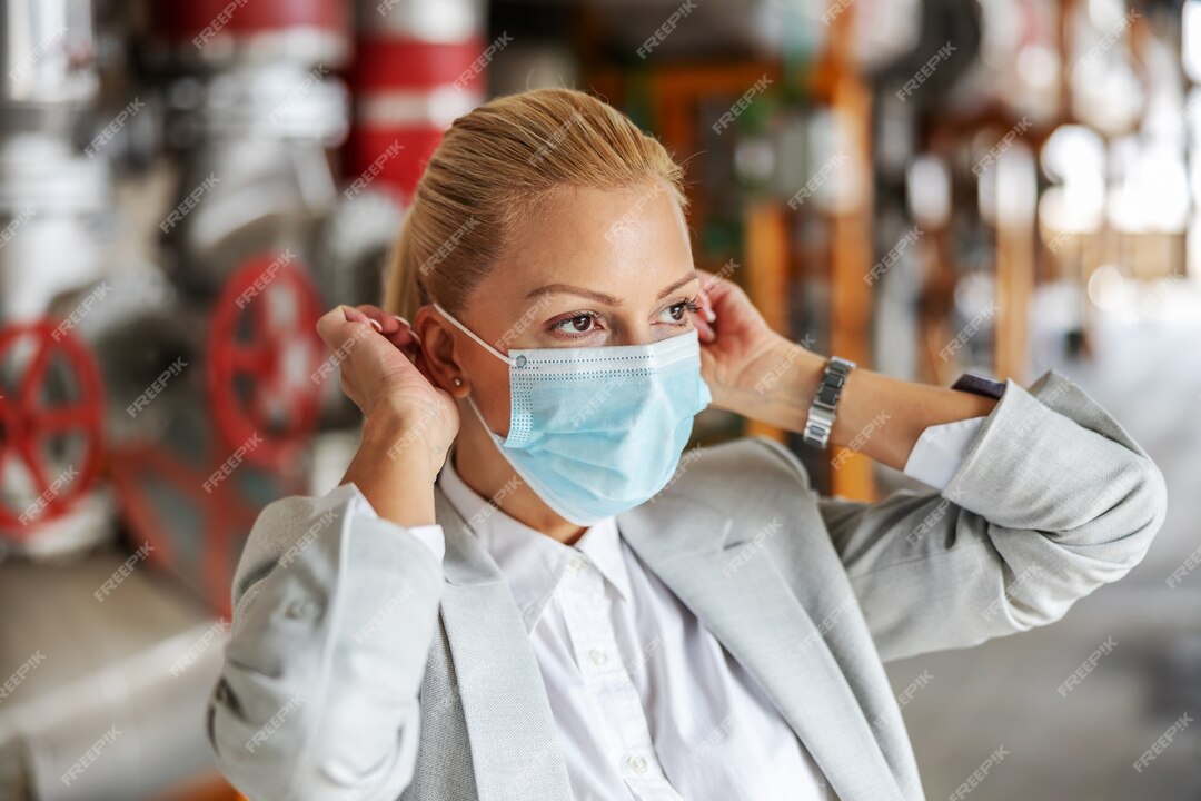closeup-blond-businesswoman-suit-putting-face-mask-while-standing-her-plant-corona-virus_232070-10367