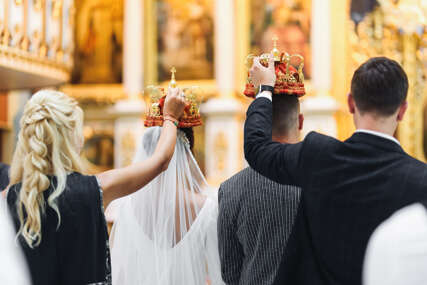 Bride and groom stand with crowns during the ceremony in church