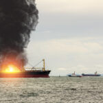 Large general cargo ship for logistic import export goods and other the explosion and had a lot of fire and smoke at sea